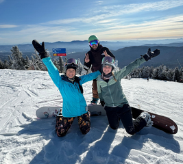 Friends snowboarding with their hands in the air