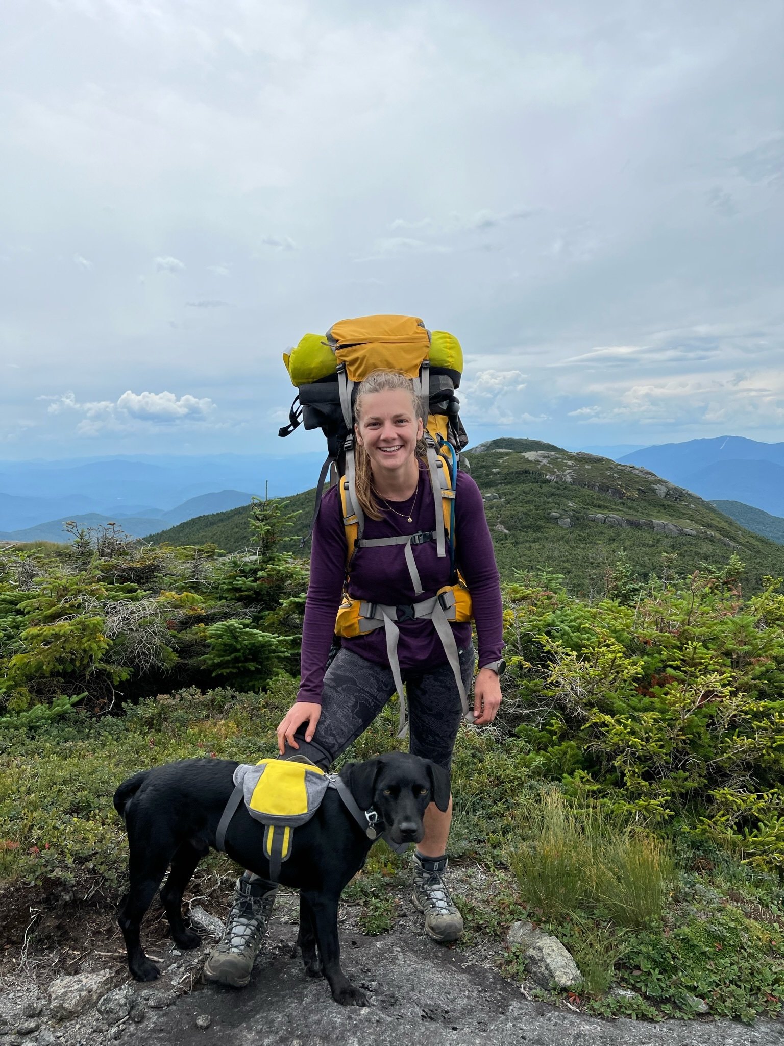 Woman in hiking gear on a trail with her dog
