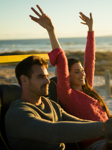 Couple driving in a convertible with hands in the air
