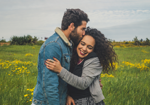 Couple holding each other in a field of grass