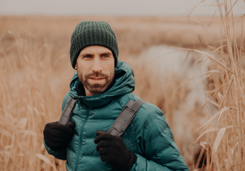 Man hiking through a field with a backpack