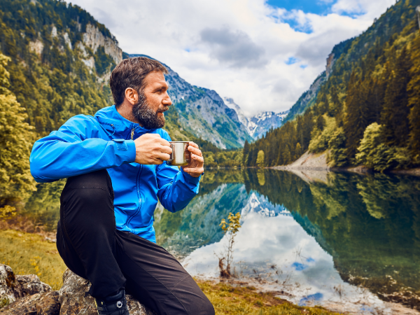 Man sitting on a rock by a lake surrounded by mountains